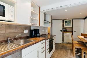 a kitchen with white cabinets and a sink and a table at Hof Timmermann - Landhaus, oben in Ottenstein