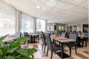 a restaurant with tables and chairs and large windows at TheOriginals City, Hôtel restaurant l'Ormichal Dijon Sud in Marsannay-la-Côte