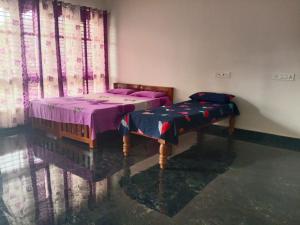 a bedroom with two twin beds with purple sheets at Shrunga Shreni Homestay - Near Bandaje trek and falls in Kalasa +3 photos