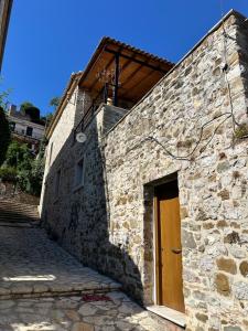 a stone building with a brown door on it at Nia The Yard in Nafpaktos