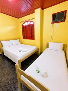 two beds in a room with a window at Sea Blue Suites in Angra dos Reis