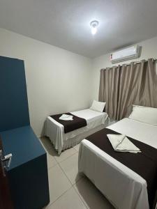 a hotel room with two beds and a window at Pousada Caribe Brasileiro in Maragogi