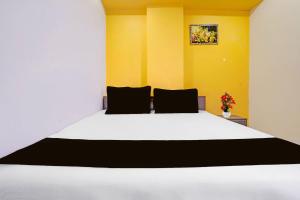 a bedroom with a large white bed with yellow walls at Hotel O Unity Guest House in Dabhoi +21 photos