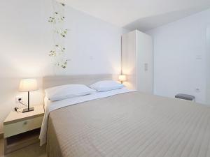 a white bedroom with a large bed with two pillows at House Gorica 2 - underground level apartments in Baška +73 photos