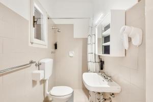 a white bathroom with a toilet and a sink at Hotel Sole in Marina di Massa +20 photos