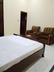 a room with a bed and chairs in it at Royal Heritage Lodges in Bahawalpur