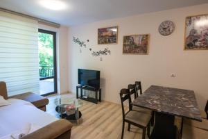 a room with a bed and a table and a television at Apart Complex Amphora Palace in Golden Sands