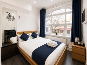a bedroom with a bed and a large window at The Broadway Hotel - London Heathrow in Southall