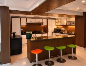 a kitchen with green and orange bar stools at Cecil Apartments On Mall Road Murree in Murree