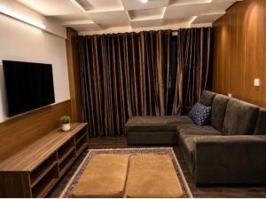 a living room with a couch and a flat screen tv at Cecil Apartments On Mall Road Murree in Murree