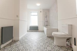 a bathroom with a toilet and a tub and a sink at Gordan Villas in Leigh