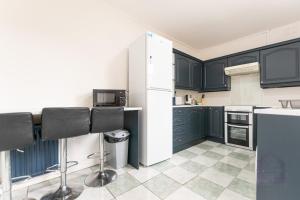 a kitchen with black cabinets and a white refrigerator at Gordan Villas in Leigh