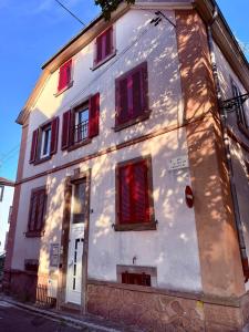a white building with red windows on a street at Le Cosy Home in Guebwiller