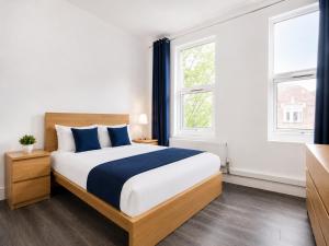 a bedroom with a large bed and two windows at The Broadway Hotel - London Heathrow in Southall