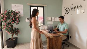 a woman in a dress standing next to a man at a desk at Hotel Boutique Mura in Cancún +33 photos