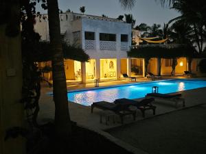 a swimming pool at night with a building at The Villa Luxury Suites Hotel in Diani Beach
