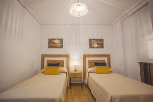 two beds with yellow pillows in a room at Castillo Buenavista in Ponferrada