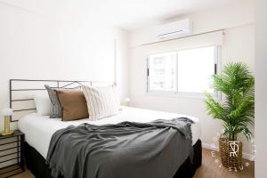 a white bedroom with a large bed and a window at Top Rentals Palermo Chico in Buenos Aires