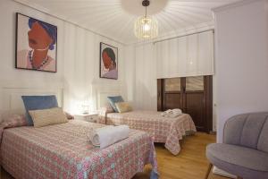 a room with two beds and a chair at Castillo Buenavista in Ponferrada