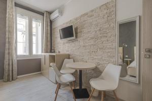 a room with a table and chairs and a brick wall at Trieste Centro Rooms-camere eleganti in pieno centro in Trieste