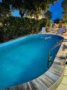 a swimming pool with a wooden deck and chairs at Hotel Angely in Eforie Nord