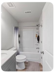a white bathroom with a toilet and a bath tub at Luxury Room In McDonough in McDonough