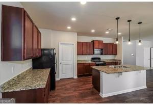 a kitchen with wooden cabinets and granite counter tops at Luxury Room In McDonough in McDonough