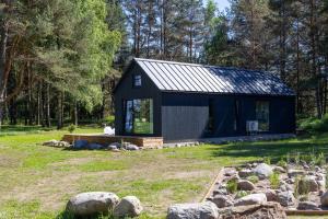 a black shed in a yard with rocks at Kasispea Meremaja in Kasispea