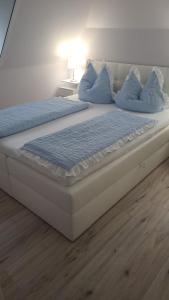 a large bed with blue pillows on top of it at Ferienwohnung Herzmuschel in Aventoft