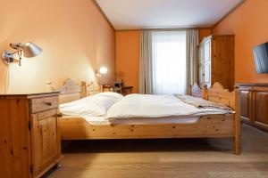 a bedroom with a wooden bed and a window at Hotel Pianta in Savognin