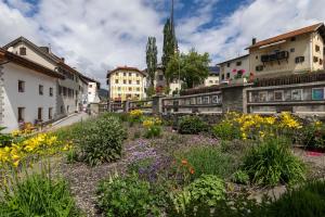 a garden in a city with buildings and flowers at Hotel Pianta in Savognin