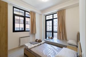 a bedroom with two beds and two windows at Stylish 2BR Apartment in Yerevan in Yerevan