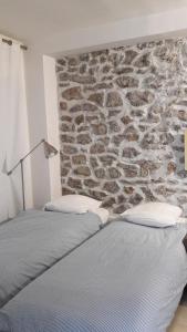 Dos camas en una habitación con pared de piedra. en Villa des iris, en París
