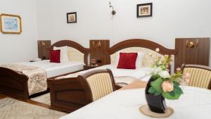 a hotel room with two beds and a vase of flowers at VILA Corviniana in Hunedoara +49 photos