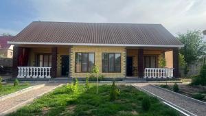 a small yellow house with a brown roof at Kapshagay Lake in Kapchagay