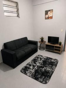a living room with a black couch and a tv at Hospedaje Encarnación Centro in Encarnación
