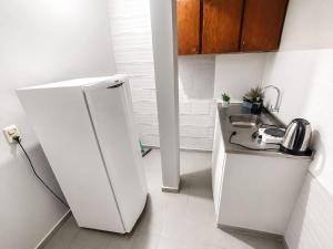 a white kitchen with a sink and a refrigerator at Hospedaje Encarnación Centro in Encarnación