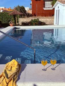 two wine glasses sitting next to a swimming pool at Chalet casa la adelfa in Chiclana de la Frontera