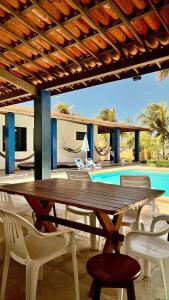 a wooden table and chairs on a patio with a pool at Casa Marina in Beberibe
