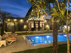 a villa with a swimming pool at night at Qafqaz Mountside Chalet in Gabala