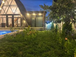 a house with a garden and a swimming pool at night at Qafqaz Mountside Chalet in Gabala
