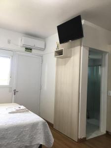a bedroom with a bed and a flat screen tv on the wall at Hotel Vanguarda Tapera in Tapera
