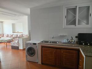 a kitchen with a sink and a washing machine at Residence Jamal Only Family in Martil
