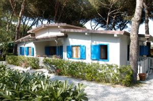 a small white house with blue shuttered windows at Parco Vacanze Camping Sogno in Marina di Massa
