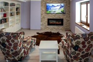 a living room with chairs and a table and a fireplace at Pokoje nad Dunajcem in Biały Dunajec