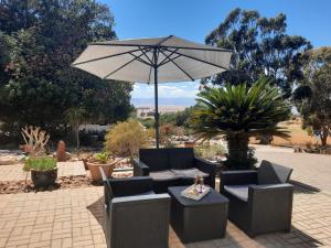 a patio with chairs and an umbrella and a table at Piketberg Home with a View in Piketberg
