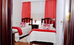 a bedroom with two beds with red curtains and red and white at Hotel Drago San Antonio in Icod de los Vinos