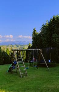 ein Spielplatz mit zwei Schaukeln und einer Rutsche in der Unterkunft Hajlanderka in Bustryk