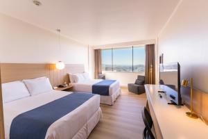 a hotel room with two beds and a television at Wyndham Concepcion Pettra in Concepción