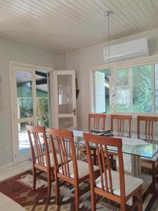 a dining room with a table and chairs and windows at Casa Verde do Lago in São Francisco de Paula